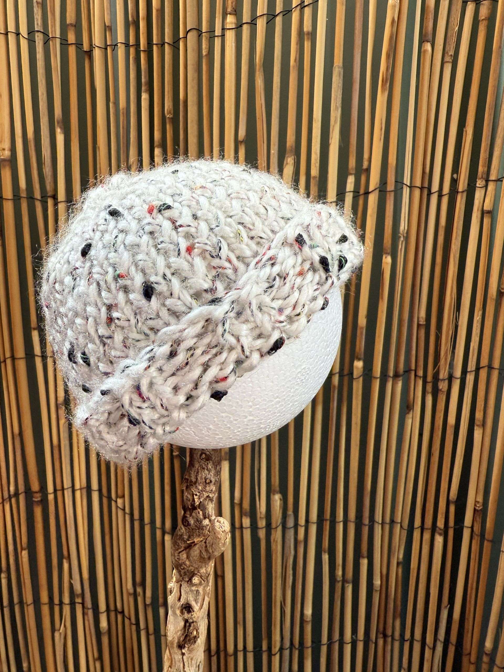 A snowy white baby beanie handmade with flecks of colour scattered through the knit like confetti.