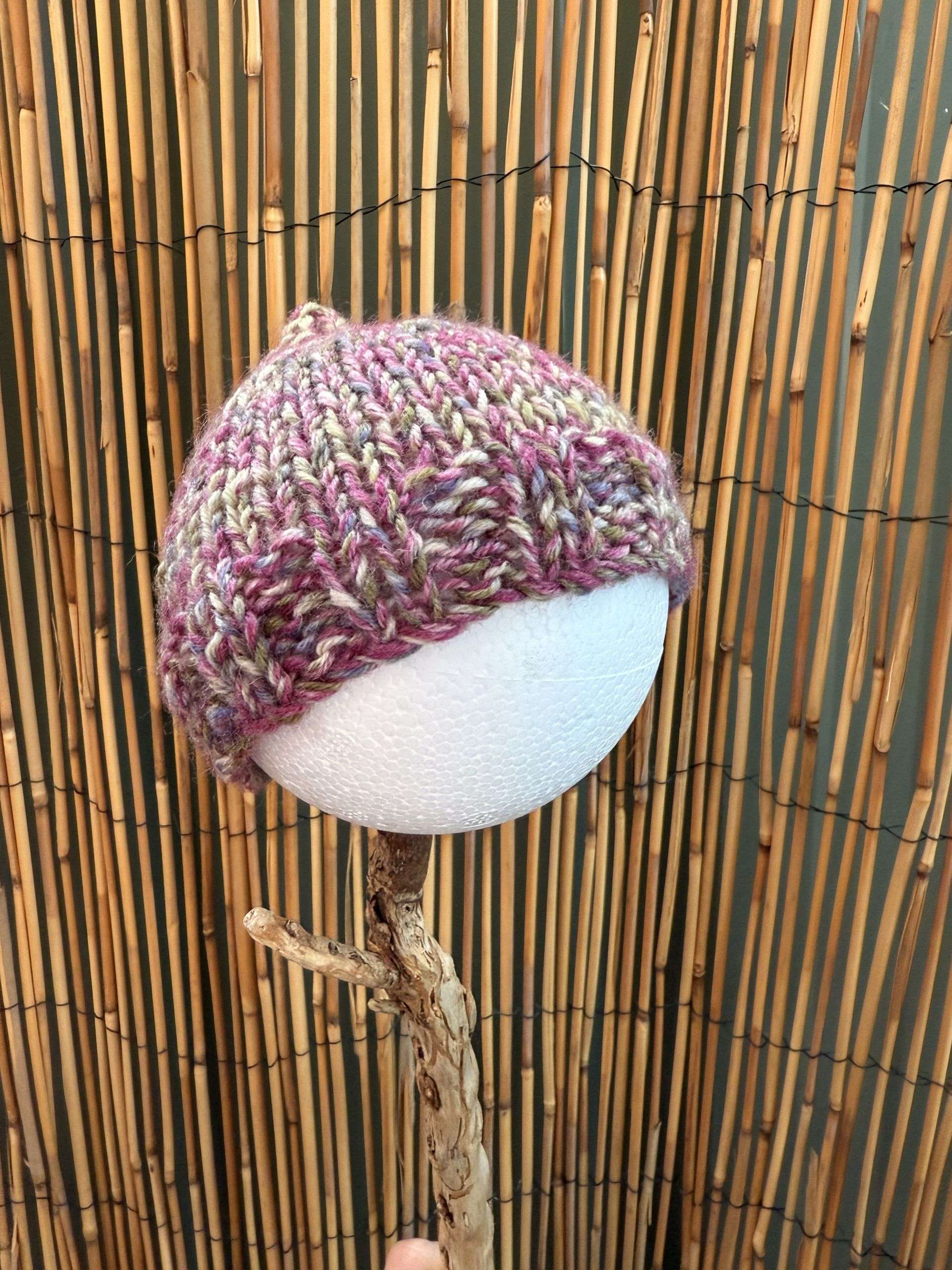 A rose and mauve marled baby beanie, handmade for newborns who deserve a bit of soft magic.