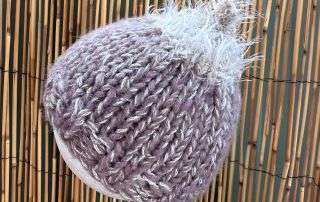 Close up of the fluffy topknot on this handknitted baby beanie, soft enough for premmies and newborns.