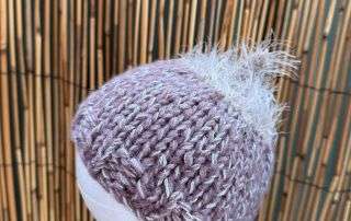 Close up of the fluffy topknot on this handknitted baby beanie, soft enough for premmies and newborns.