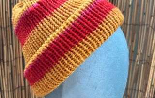 Bold gold and red stripes make this handknitted beanie one of our sunniest adult beanies for winter.