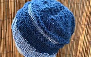 A slouchy blue and white adult beanie, handknitted in panels for a relaxed, storybook silhouette.