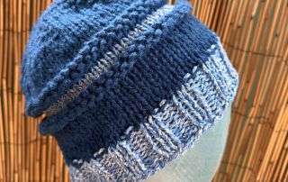 A slouchy blue and white adult beanie, handknitted in panels for a relaxed, storybook silhouette.