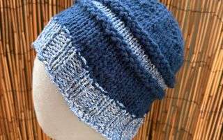 A slouchy blue and white adult beanie, handknitted in panels for a relaxed, storybook silhouette.