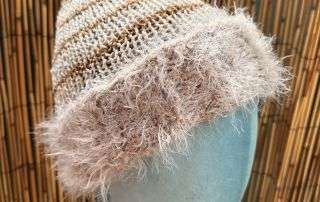 A creamy handknitted beanie with a fluffy contrast brim, one of our cosiest adult beanies for winter walks.