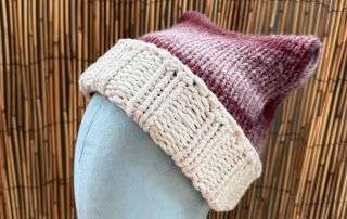 Side view of our berry marl cat ear beanie, cream cuffed and ready for anyone who never grew out of make believe.