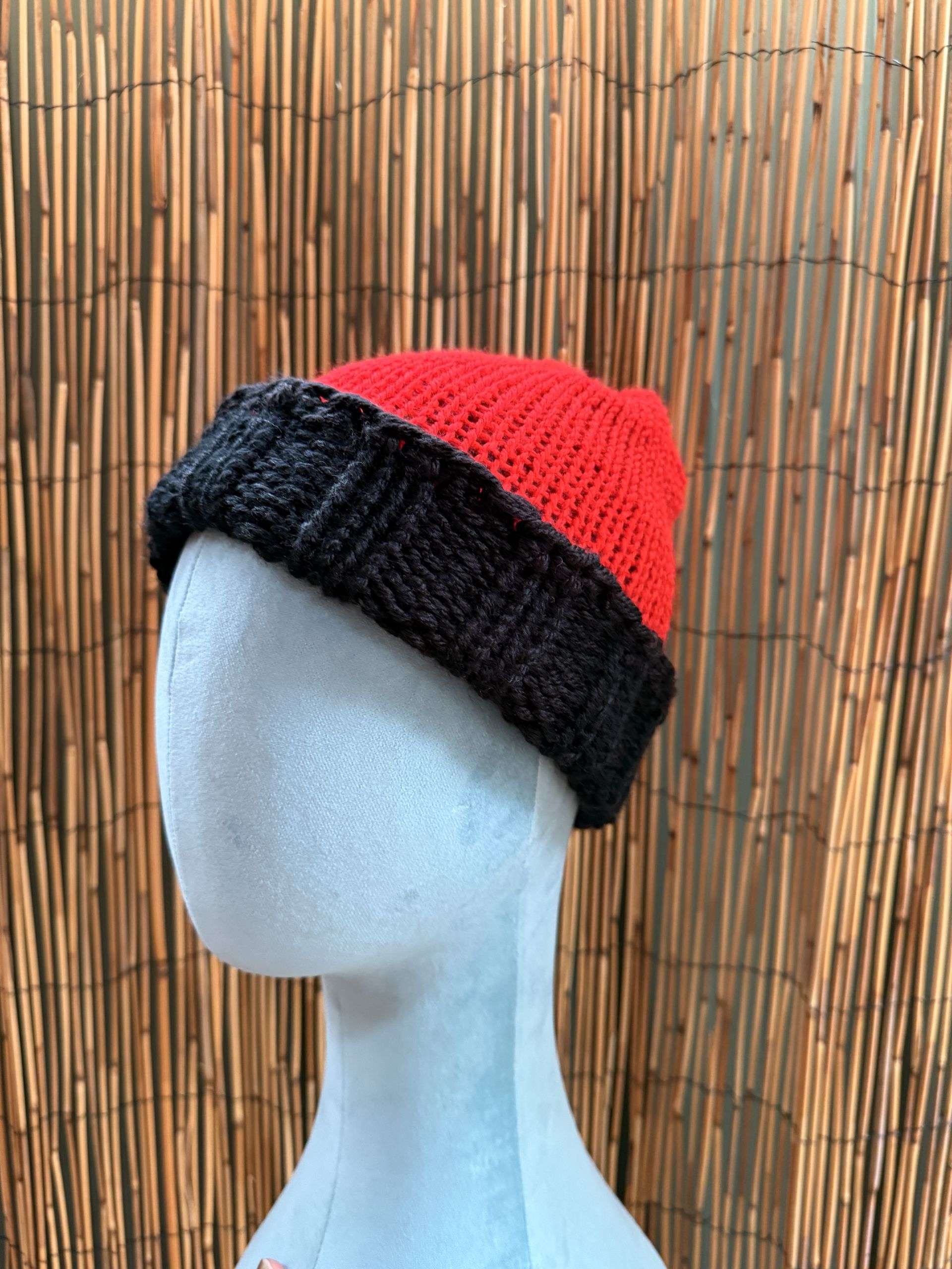 Bold red on the outside, moody black beneath, this reversible adult beanie is handknitted for double the drama.