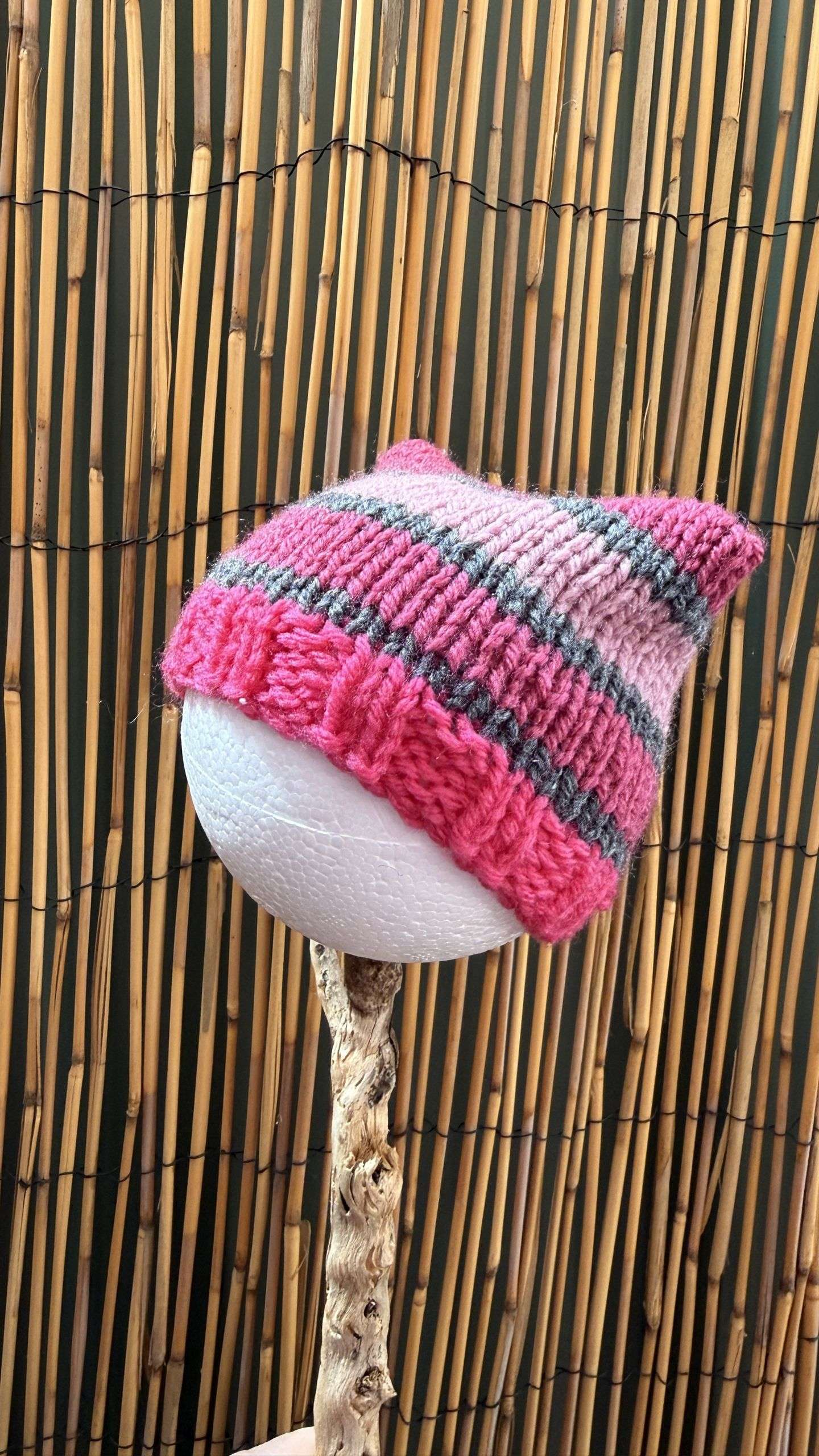 A pink and rose cat ear beanie handmade with a playful stripe and a perky little ear, sized for the smallest of heads.