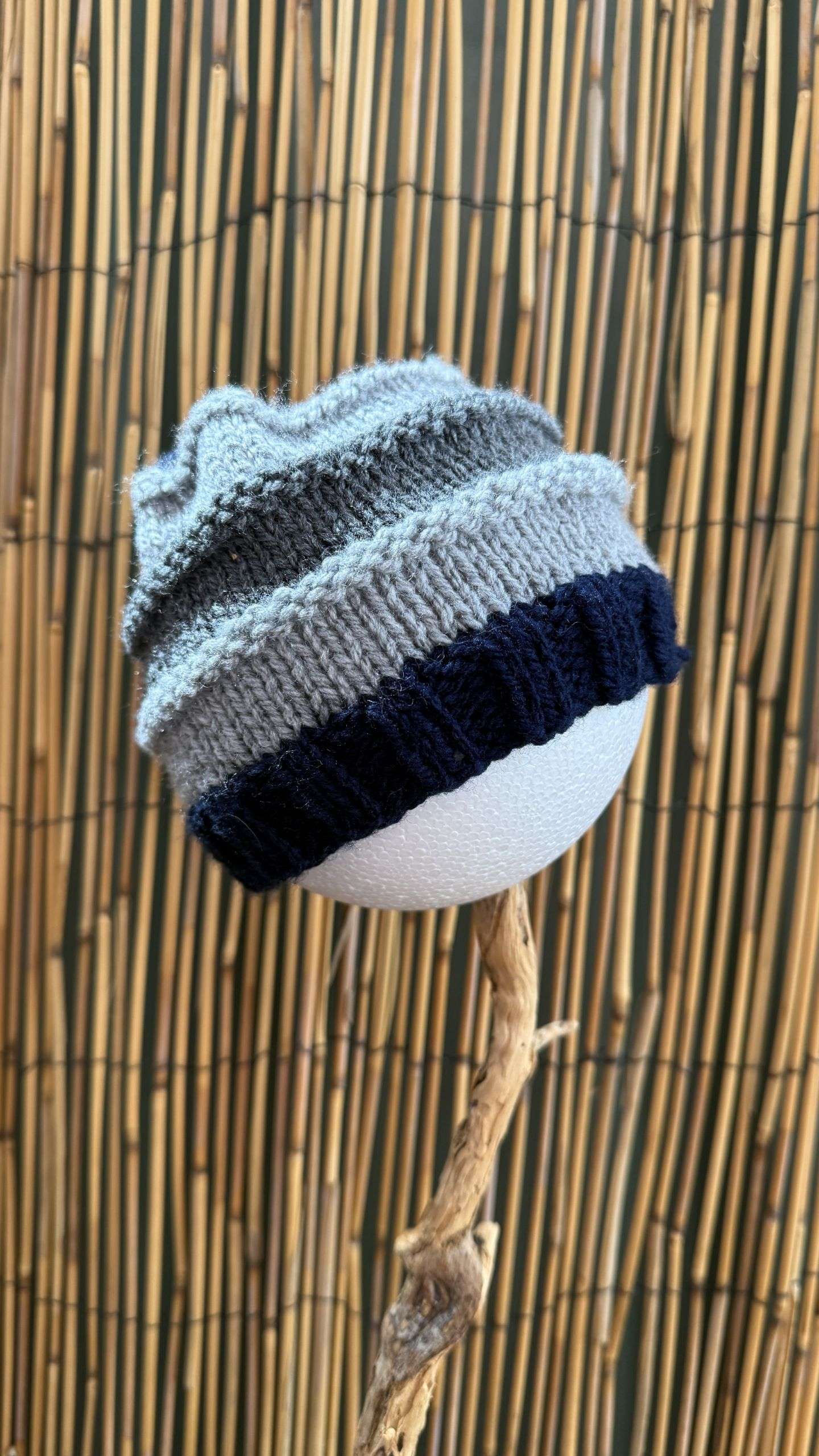 A grey and blue striped toddler beanie, handknitted with a cosy navy cuff for everyday polish.