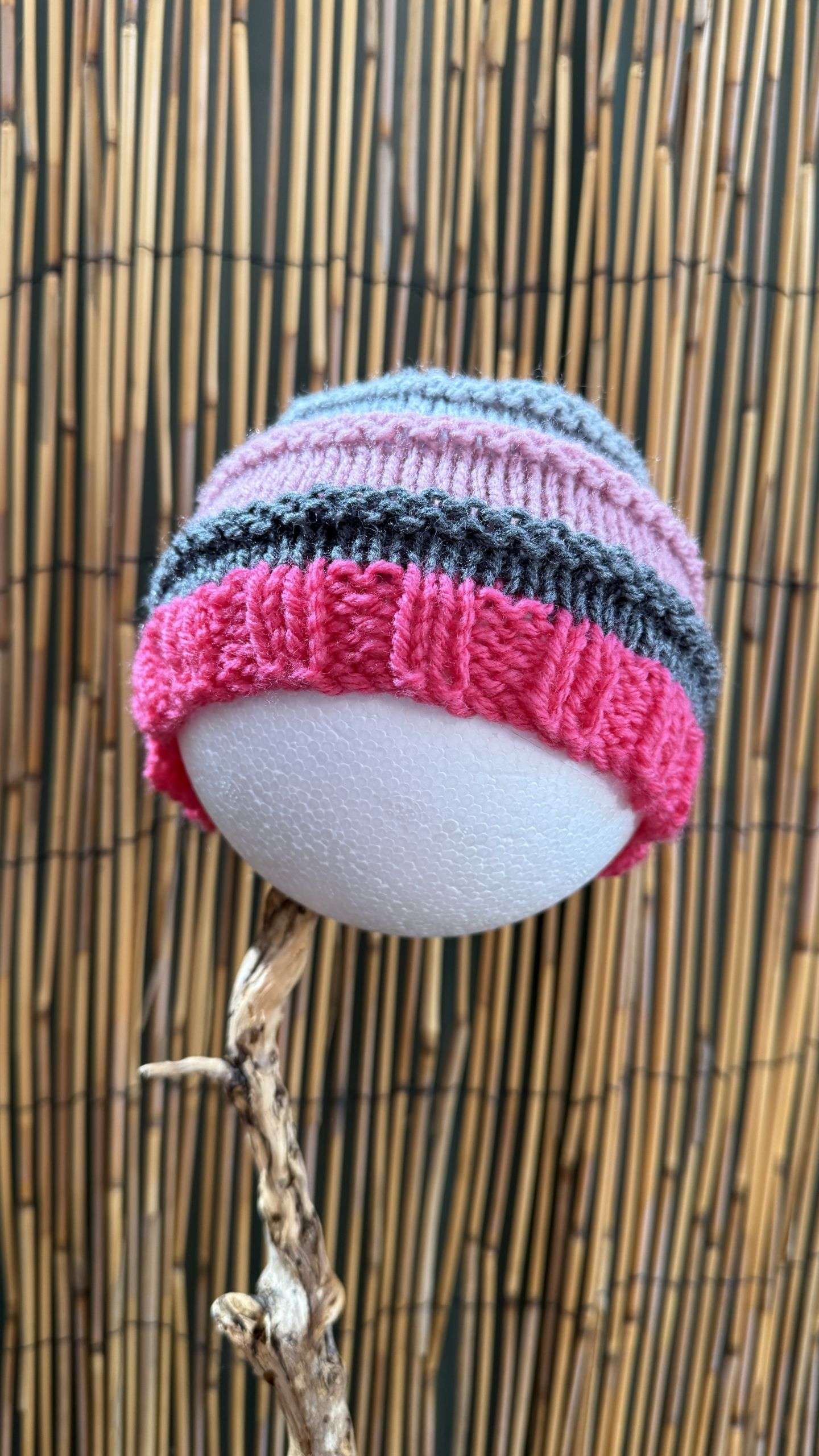 A playful pink and grey striped toddler beanie, handknitted stitch by stitch for cosy days out and about.
